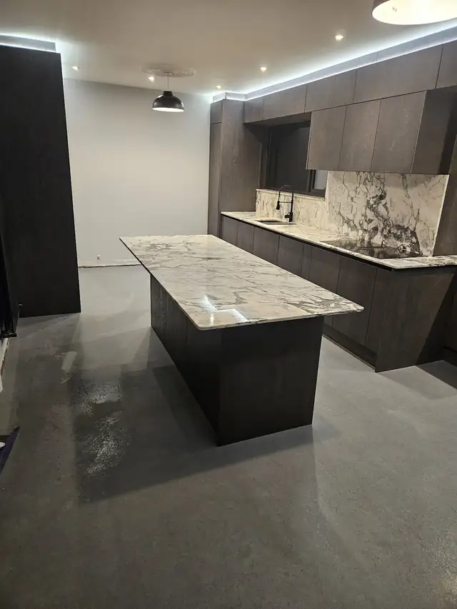 Dark wood kitchen island with a marble effect worktop in an open plan kitchen