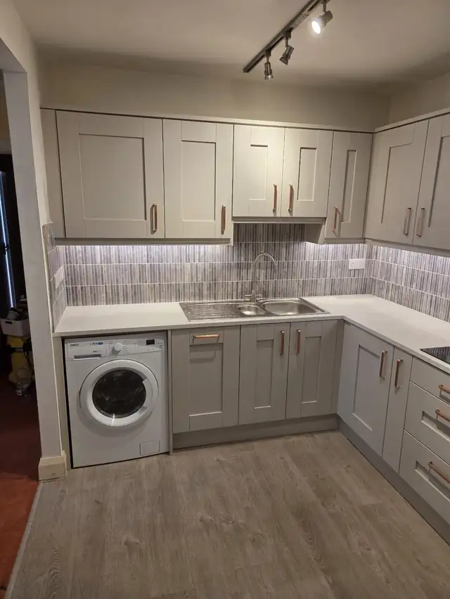 Light grey shaker kitchen with white worktops and patterned splashback tiles